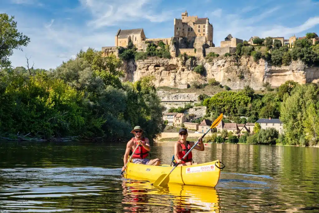 Couple qui pageaiu dans Canoës jaune de canoës Loisirs devant le chateau de Beynac en Dordogne