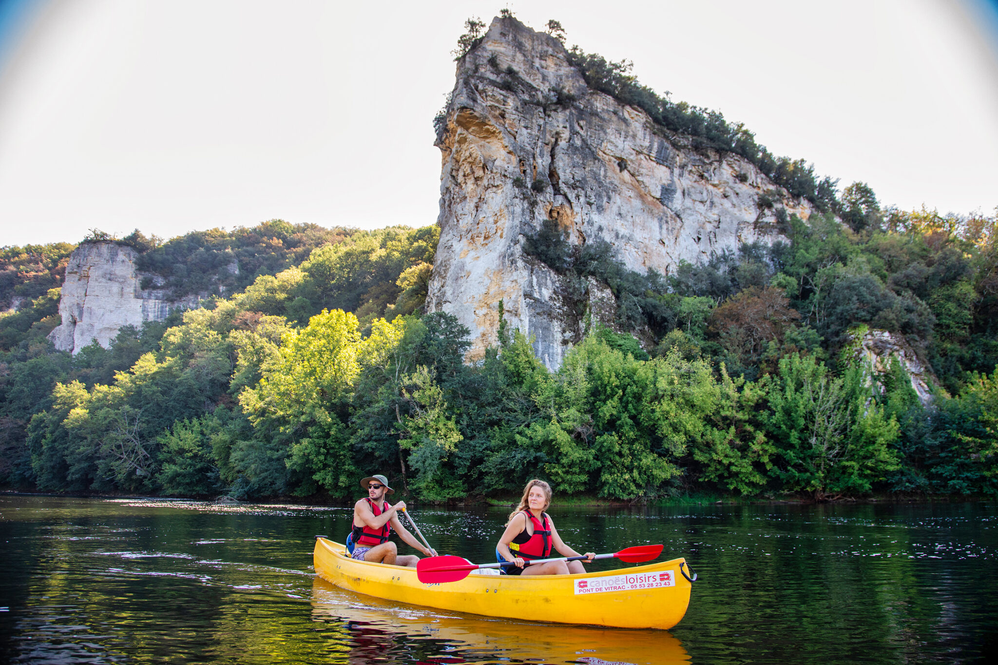 Couple en canoë jaune de Canoës Loisirs devant le Rocher de Caudon