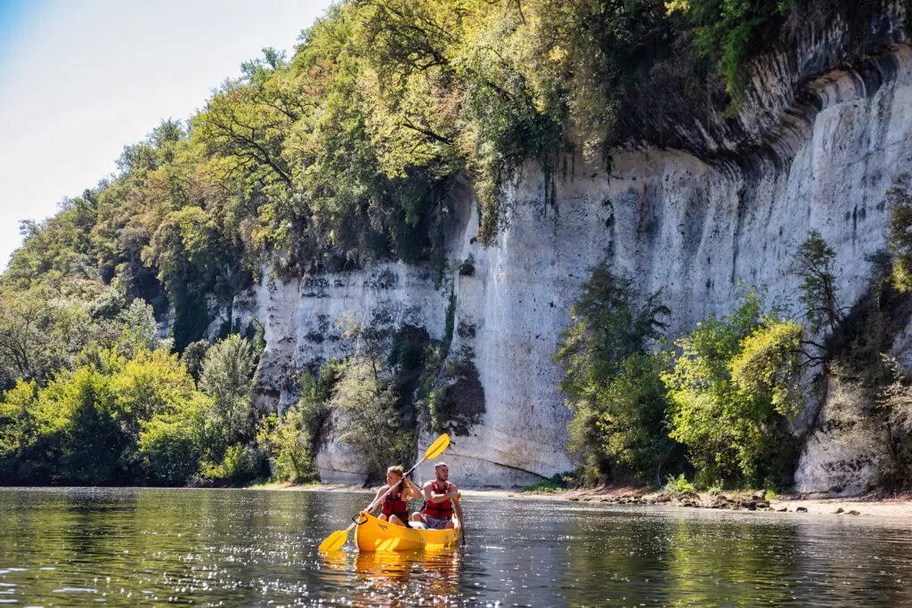 Canoë jaune devant les falaise Pendoille sur le parcours vitrac Castelnaud - Canoës Loisirs