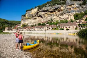 Couple à côté de leur canoë jaune devant la Roque Gageac