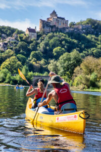 Couple dans canoë jaune de la base Canoës Loisirs en Dordogne qui descent la Dordogne en apercevant le chateau de Castelnaud-la-chapelle