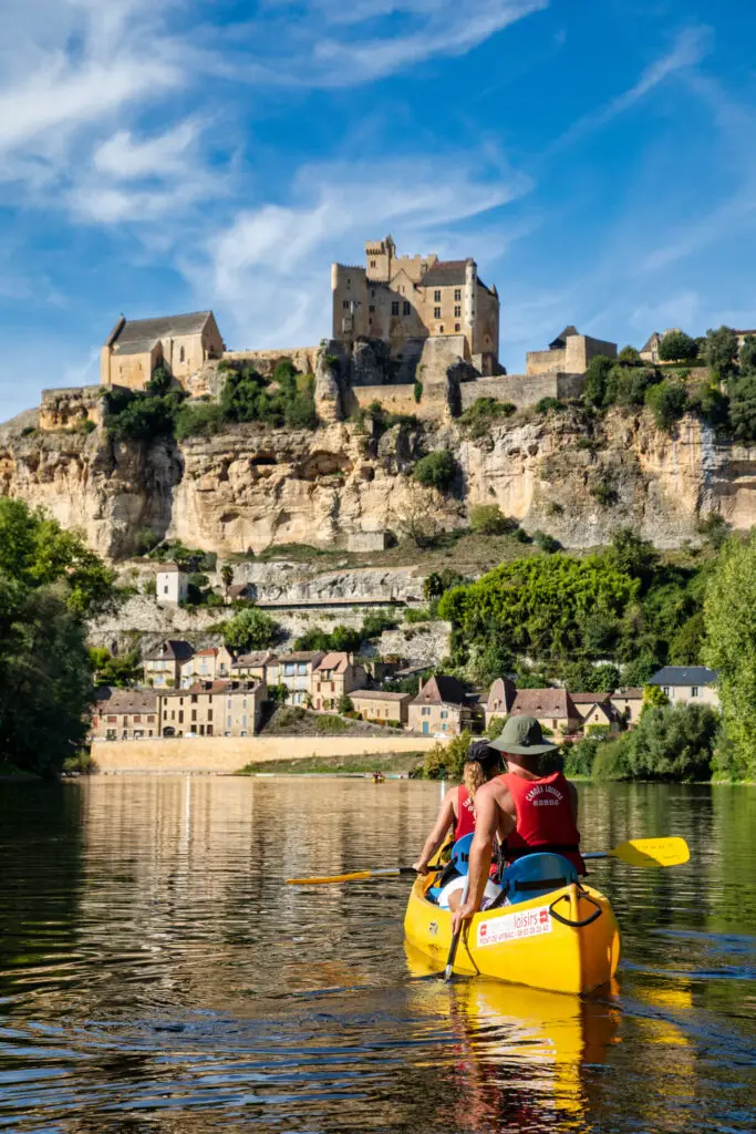 Couple dans Canoë jaune Canoës Loisirs devant le chateau de Beynac